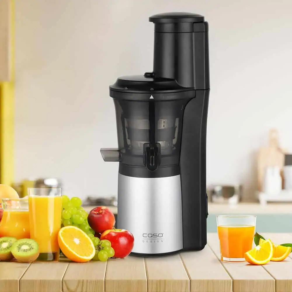عصارهگیر کندسرعت CASO SJW 300 روی میز آشپزخانه همراه با آب پرتقال تازه