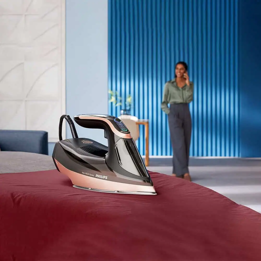 اتوی فیلیپس DST8041 قرار گرفته روی تخت با طراحی مدرن و بخاردهی آماده به کار در محیط خانگی