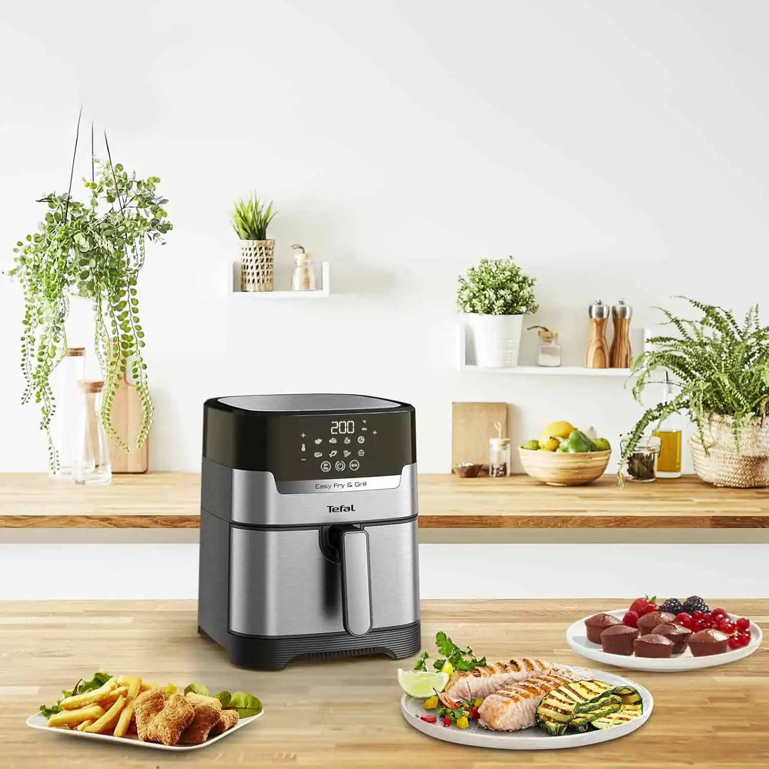 سرخکن بدون روغن و گریل دیجیتال تفال EY505 روی میز آشپزخانه با غذاهای متنوع آماده سرو